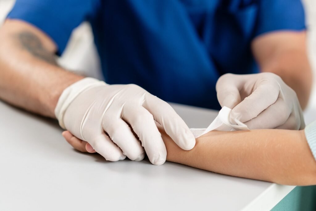 Healthcare professional wearing gloves applying a bandage to a patient's arm