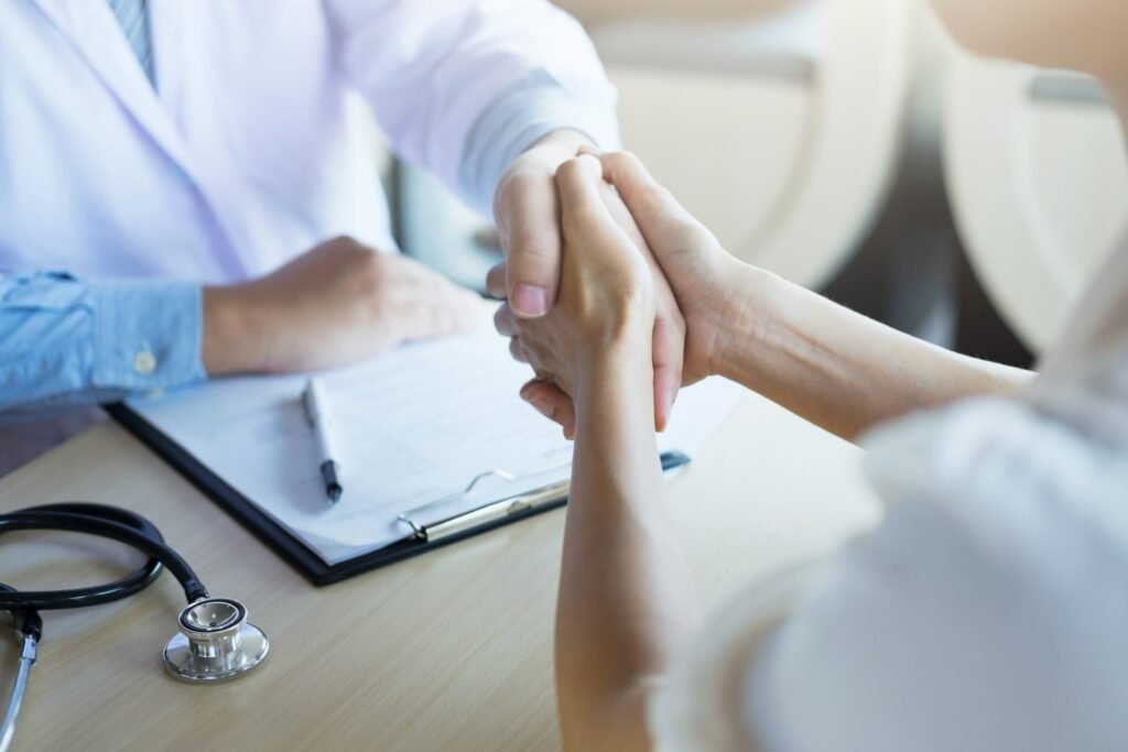 Male doctor in white coat shaking hands with female patient in clinic