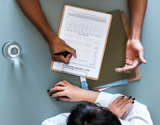 Doctor reviewing patient’s daily progress form at a clinic desk with medical documents