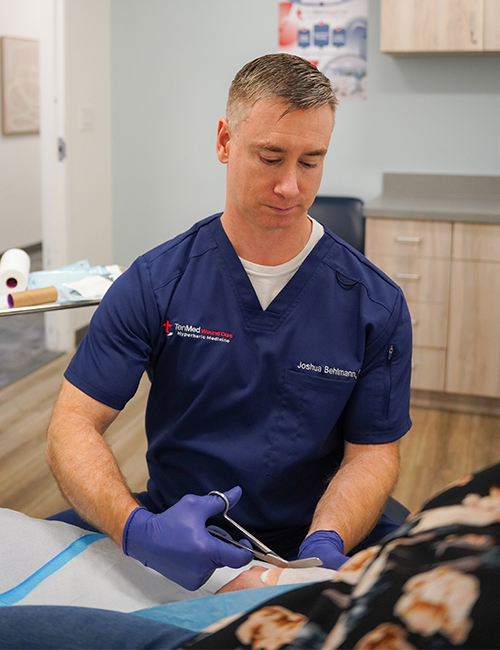 Dr Joshua Behlmann treating wound at TenMed